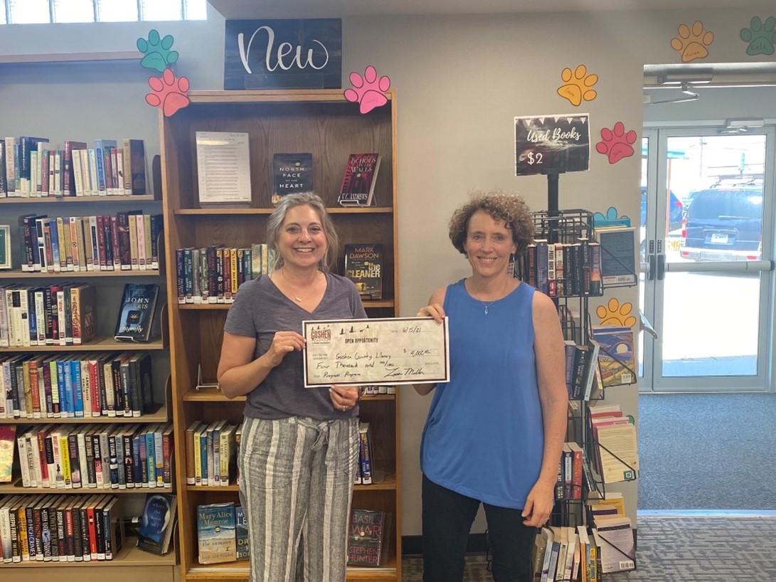 two women holding a check in a bookstore