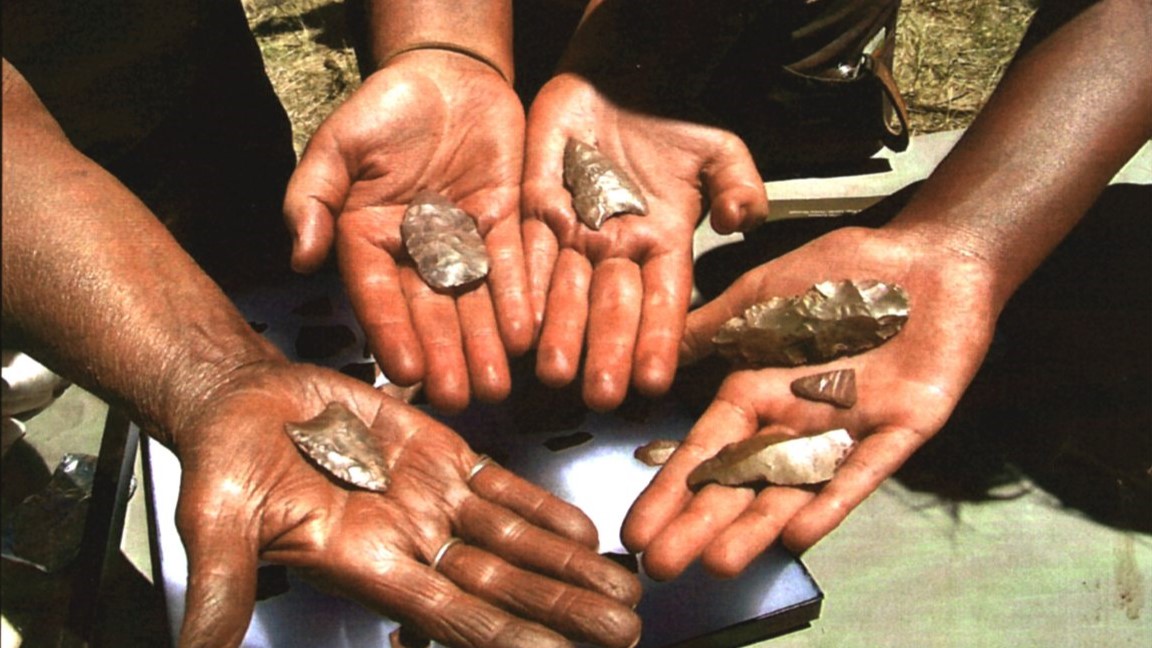 a closeup of hands holding arrowhead artifacts