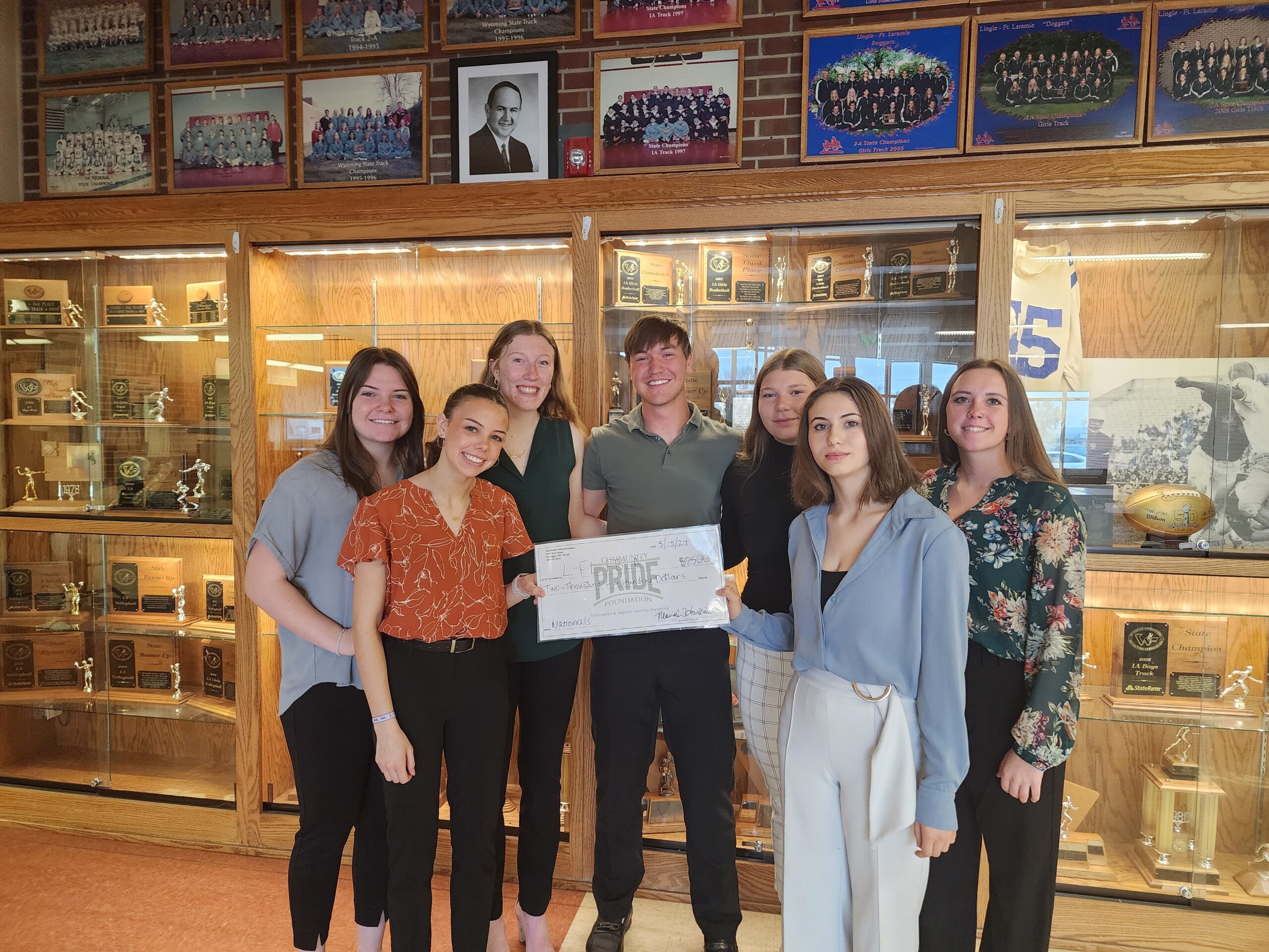 Photo of students standing in front of a trophy case.